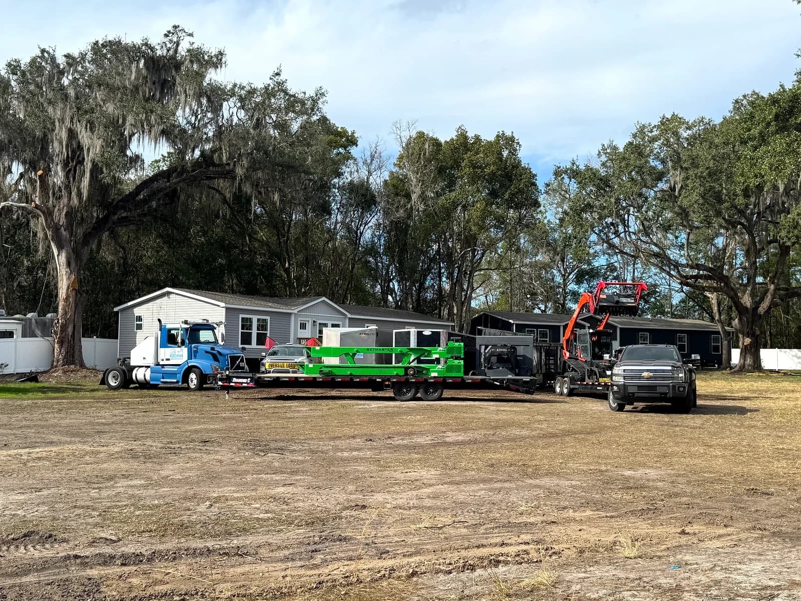 Trinity flatbed loaded with construction equipment for a mobile home setup